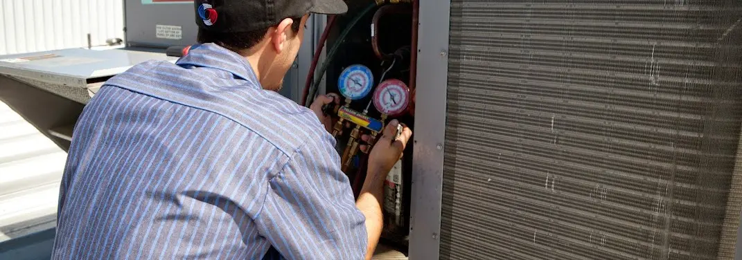HVAC technician servicing a condenser unit in Fairfax